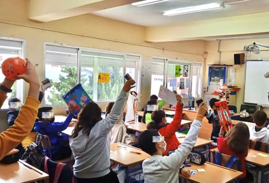 Niños en un aula levantan materiales reciclados durante un taller sobre economía circular.
