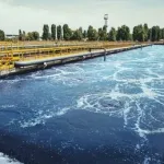 Planta de tratamiento de aguas residuales con grandes depósitos de agua en proceso de purificación al aire libre.